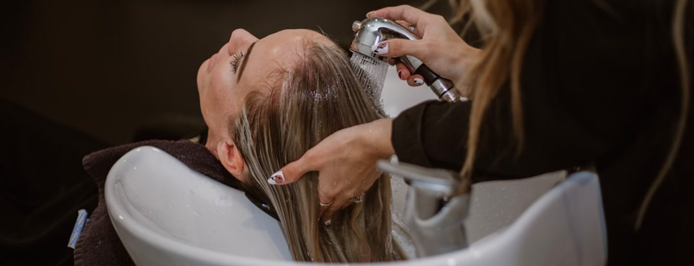 Thợ gội đầu đang làm cho khách tại salon — nghề nhận khách theo lịch hẹn từng thợ